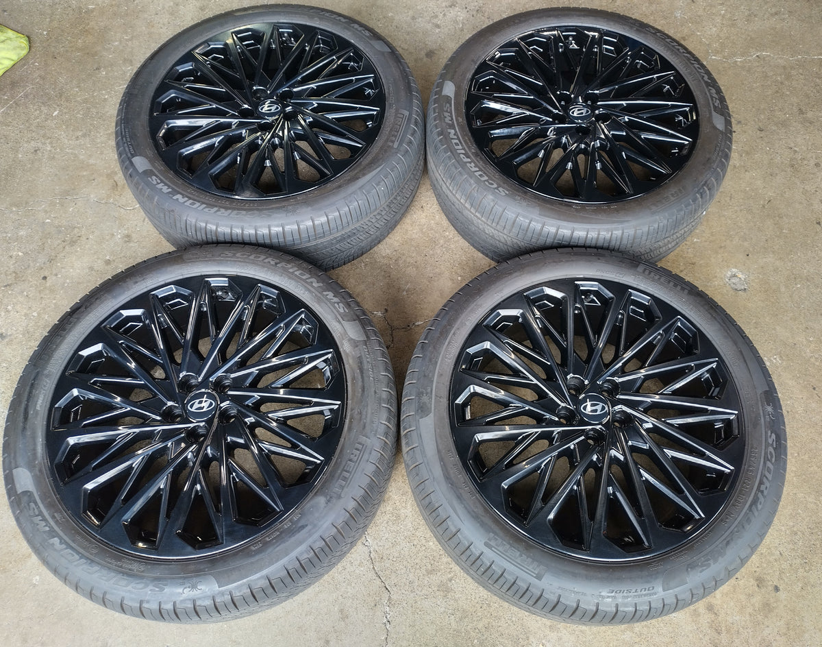 Four Hyundai Palisade Calligraphy OEM 21-inch gloss black multi-spoke wheels with Pirelli tires and Hyundai center caps.