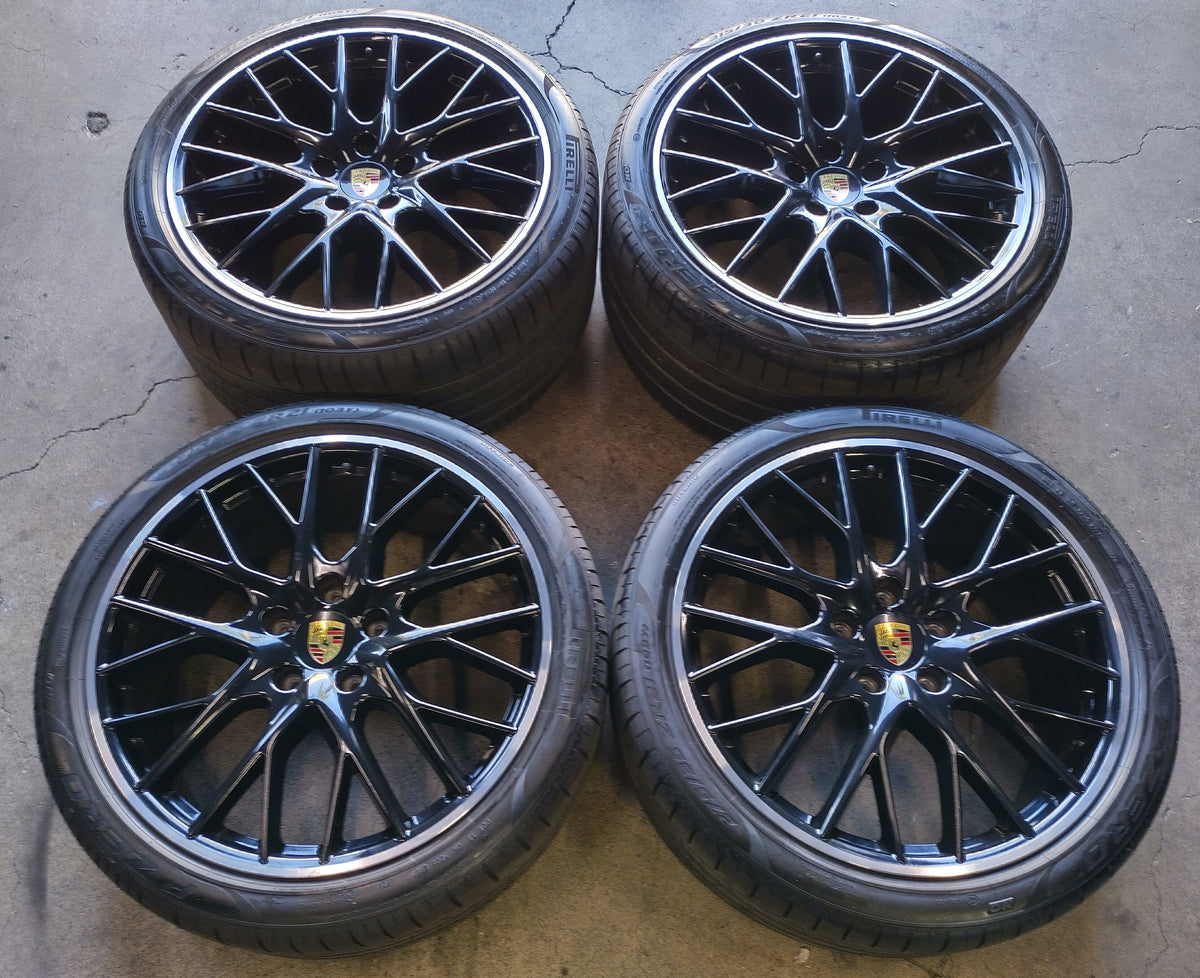 Four Porsche Panamera black multi-spoke wheels with machined lips, Porsche center caps and mounted Pirelli tires.