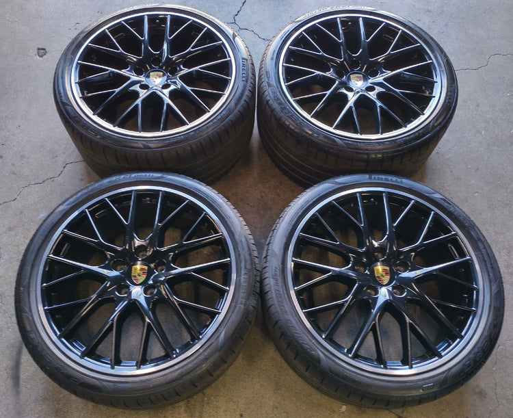 Four Porsche Panamera black multi-spoke wheels with machined lips, Porsche center caps and mounted Pirelli tires.