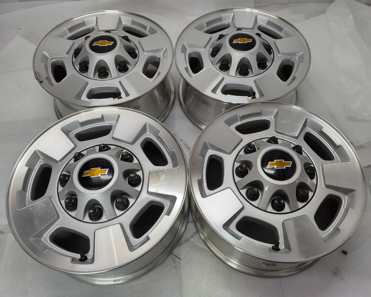 Four used Chevrolet Silverado 17-inch machined silver OEM wheels with Chevrolet bowtie center caps and visible cosmetic blemishes.