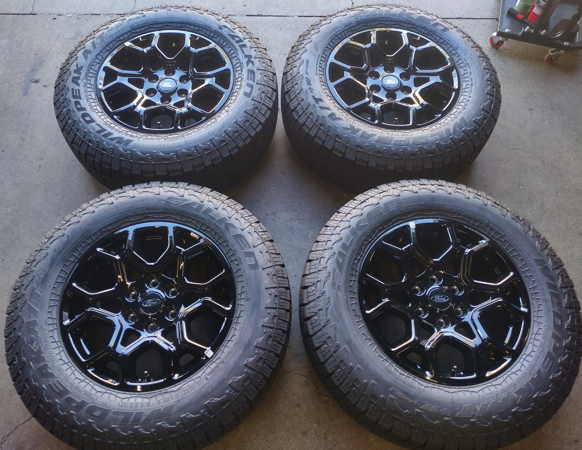 Four Ford F-150 OEM 18-inch gloss black wheels with Falken Wildpeak all-terrain tires and Ford center caps.