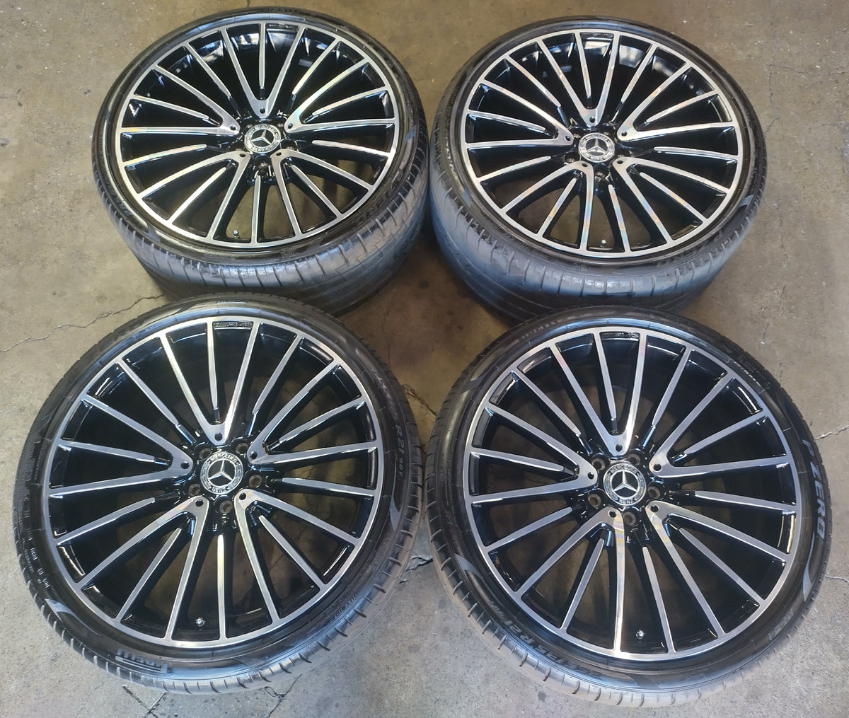 Set of four Mercedes-Benz AMG 21-inch multi-spoke wheels with machined faces, black pockets, mounted tires and Mercedes center caps.