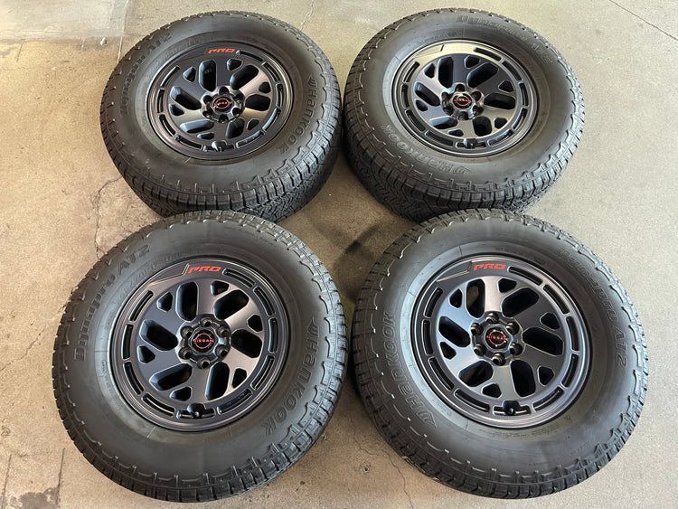 2024-2026 Nissan Frontier X-PRO OEM 17 inch Semi Gloss Black Wheel Rim Tire Set of 4, 17x7.5 wheels with 6x114.3 bolt pattern and +30 mm offset, OEM numbers 188183 and 40300-9BY2A, interchange 62270, Hankook Dynapro AT2 265/70SR17 tires
