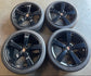 Set of four gloss black Porsche 911 wheels with mounted Goodyear tires and Porsche crest center caps.