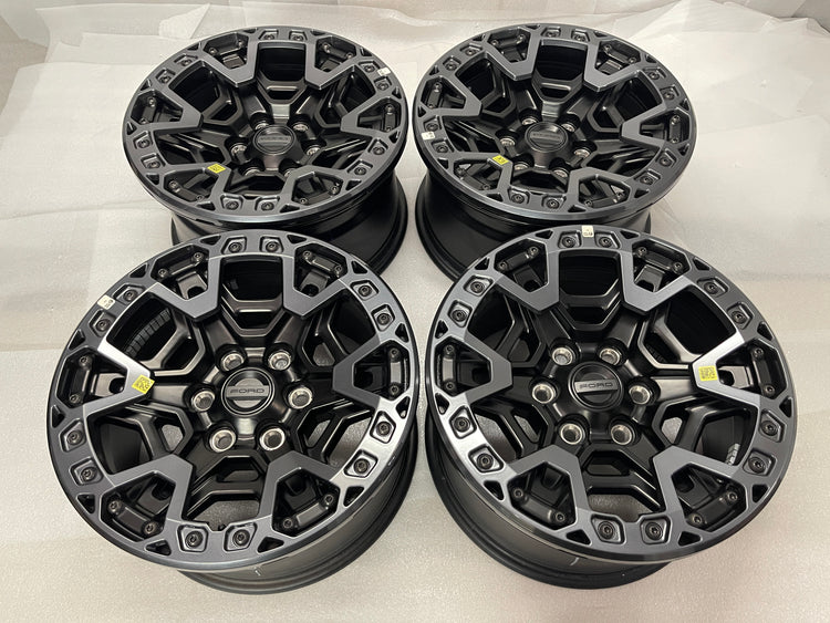 Four Ford F-150 Raptor R OEM wheels in black and gray with beadlock-style rings and Ford center caps.