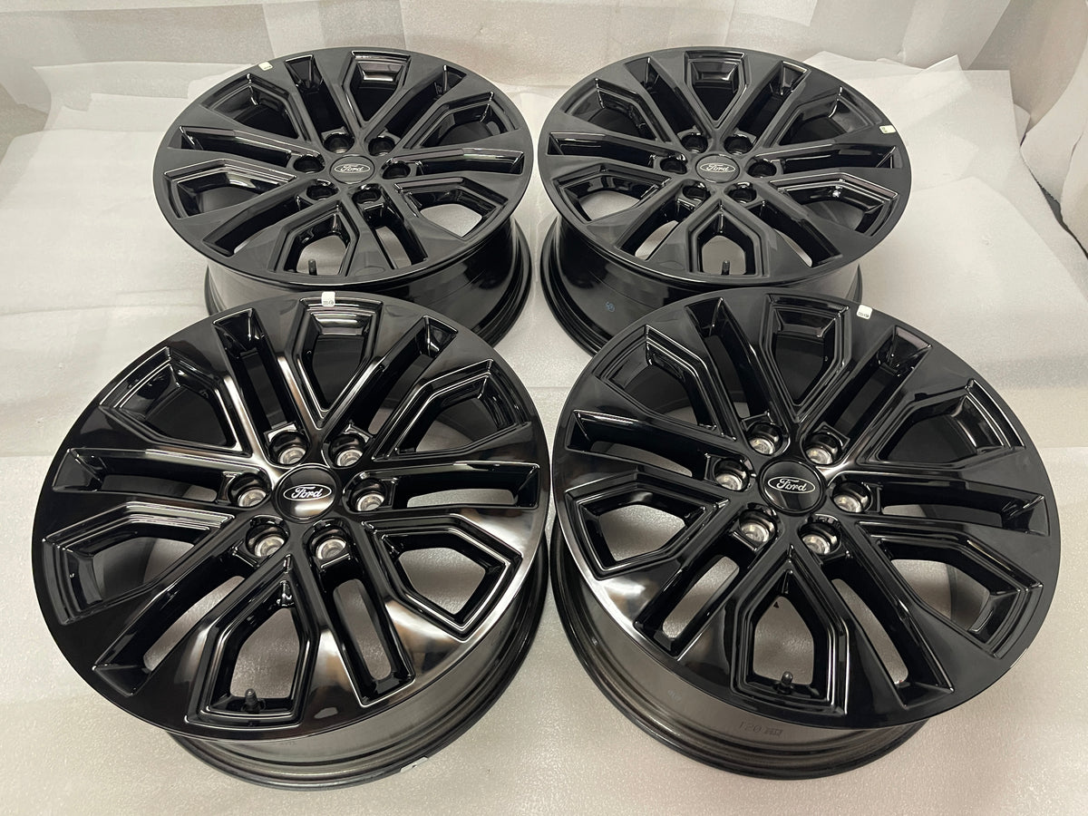Set of four gloss black Ford F150 Lariat OEM multi-spoke wheels with Ford center caps.