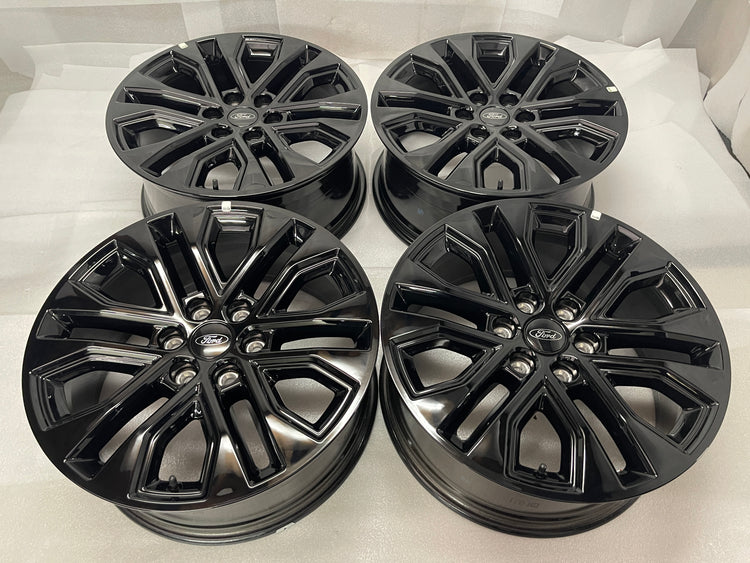 Set of four gloss black Ford F150 Lariat OEM multi-spoke wheels with Ford center caps.