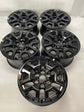 Five gloss-black Ford OEM 17-inch wheels arranged in rows, with four Ford center caps and one uncapped wheel in front.