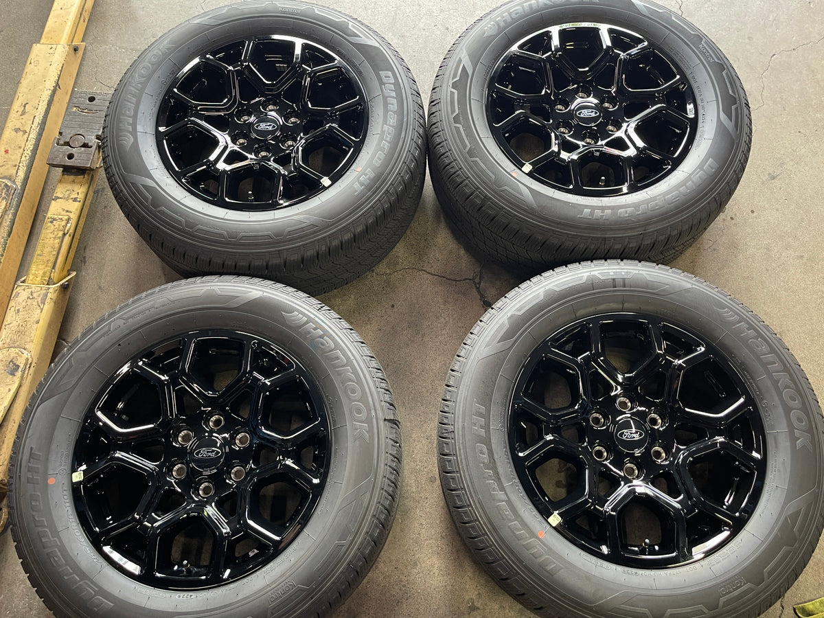 Four Ford F-150 OEM 18" gloss black wheels with Ford center caps and Hankook Dynapro H/T tires