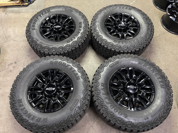 Four gloss-black Chevrolet Silverado ZR2 OEM wheels with Goodyear Wrangler Territory MT tires and Chevrolet center caps.